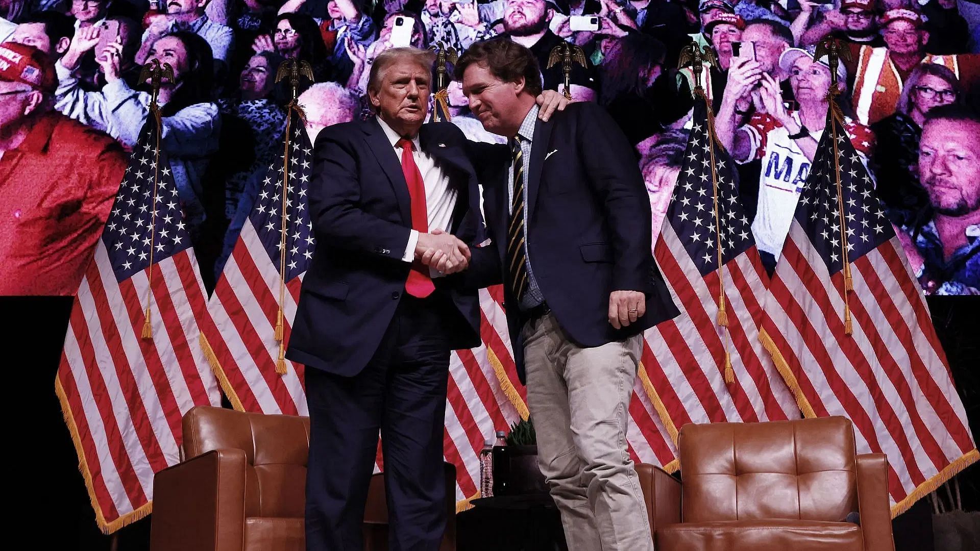 President Donald Trump shakes hands with Tucker Carlson at the conclusion of a conversation during Carlson's Live Tour (Image via Getty)